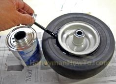 a person is painting the rim of a tire with a paint roller and an empty can