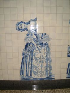 a blue and white tile wall with an image of a woman wearing a long dress