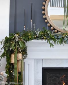 a fireplace decorated for christmas with greenery and candles