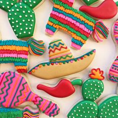 decorated cookies with different colors and shapes on a white tablecloth are arranged in the shape of cactuses