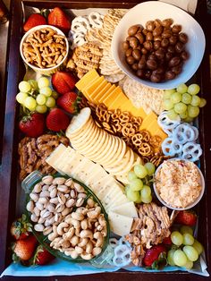 an assortment of cheeses, crackers, nuts and fruit arranged in a tray