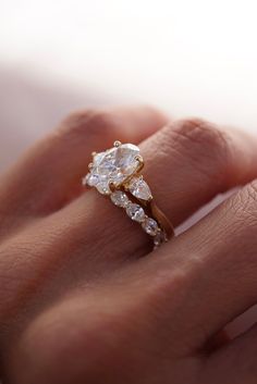 a woman's hand with a diamond ring on top of her finger and an engagement band