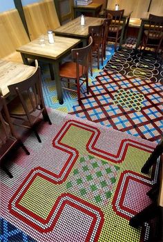 a restaurant with tables and chairs on the floor covered in colorful carpeted tiles that looks like they have been made out of legos