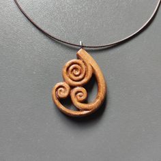 a wooden necklace with two spirals hanging from it's side on a gray surface