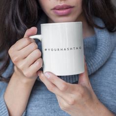 a woman holding a white coffee mug with the words somebody printed on it in front of her face