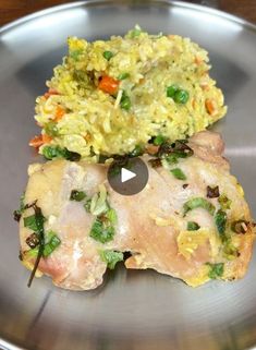 two pieces of chicken on a plate with rice and vegetables