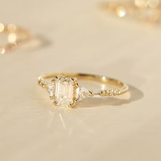 an engagement ring with three diamonds on it and two other rings in the back ground