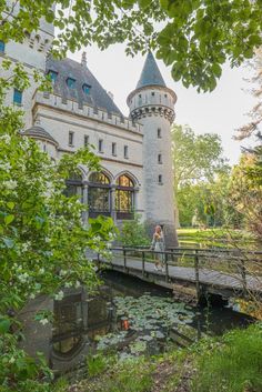 a woman walking across a bridge near a castle