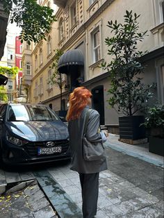 a woman with red hair is walking down the street