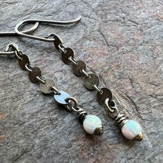 "A pair of tiny glowing Opal beads are wrapped in sterling silver. The 4mm simulated Opals dangle from chains made of small sterling silver circles. The earrings hang from handmade sterling silver earwires. Be sure to see all photos and video for size and color reference. Select your desired finish when ordering. The earrings in the main photograph are in the \"Patina: Oxidized\" finish. You can find the rest of my shop here wisehandmadejewelry.etsy.com Wise Handmade Jewelry is an eco-conscious Sterling Silver Jewelry With White Beaded Chain, Minimalist Silver Jewelry With Dangling Beads, Silver Beaded Chain Drop Earrings, Silver Teardrop Beaded Chain Jewelry, Round Beaded Chain Earrings Gift, Round Beaded Chain Earrings For Gift, Sterling Silver Long Drop Jewelry With Dangling Beads, Sterling Silver Jewelry With Dangling Beads, Dainty Silver Earrings With Round Beads