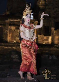 a woman dressed in traditional thai garb and holding her hand out to the side