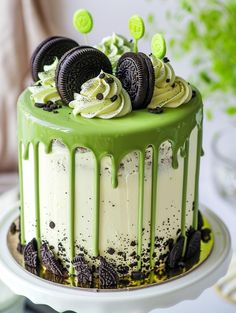 a green cake with oreo cookies and white frosting on top is sitting on a plate