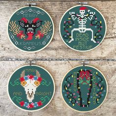 three cross - stitch hoops with designs on them hanging from a wooden wall next to each other