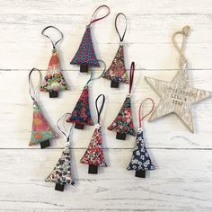 six christmas tree ornaments are hanging on a white wooden wall with a star ornament in the middle