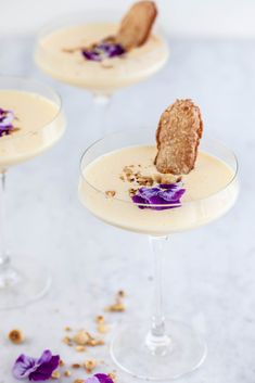 three glasses filled with dessert and garnished with purple flowers