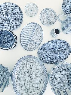 blue and white plates are arranged in a circle on a tablecloth with black dots