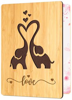 an elephant and its baby are in the shape of a heart on a wooden plaque