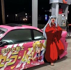 a woman standing next to a pink car in front of a gas pump at night