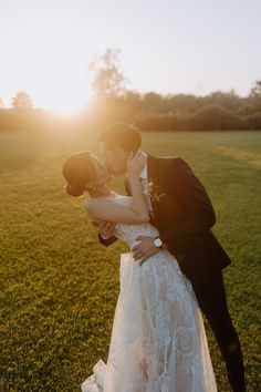 a bride and groom kissing in front of the sun on their wedding day at sunset