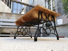 a wooden table sitting on top of a cement ground next to a building and potted plant