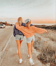 two girls walking down the road with their arms around each other and one holding her back