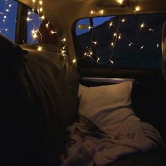 there is a bed in the back of a van with lights on it and pillows