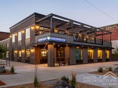 an industrial building with lots of windows and lights on the outside, in front of a red brick building