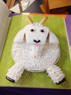 a cake shaped like a goat sitting on top of a table next to an open book