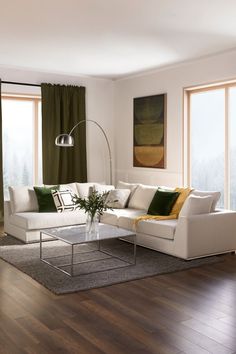 a living room with wood floors and white couches in front of large windows on the wall