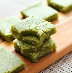 some green food is stacked on top of each other and placed on a wooden cutting board