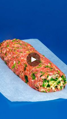 a large piece of food sitting on top of a blue paper wrapper next to a knife