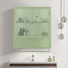 a green cabinet with glass doors and drawers in a white room next to a mirror