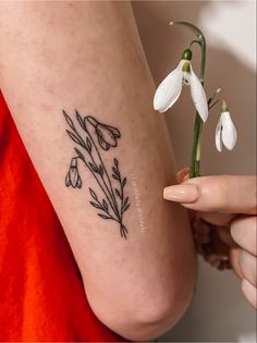 a woman holding a small flower tattoo on her arm