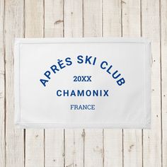 a white towel with the words apres ski club in blue on it hanging from a wooden wall