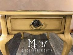 an old table has been painted gold with black knobs on it and the words m & s embellishments are in white lettering