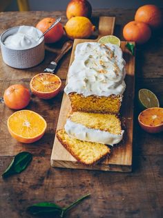 slices of orange cake with icing on a cutting board surrounded by citrus and other fruit