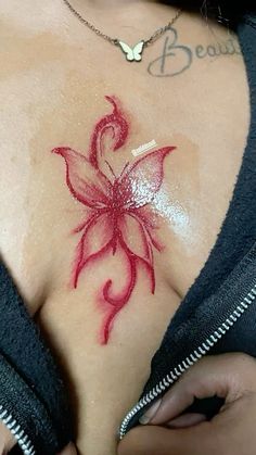 a woman's chest with a red flower tattoo on it