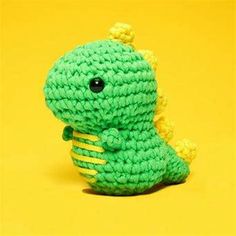 a small green crocheted toy sitting on top of a yellow surface