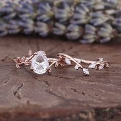 two rose gold wedding rings with white topazte and leaves on them, sitting on a piece of wood