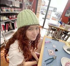 a woman sitting at a table in front of a sewing board with scissors on it