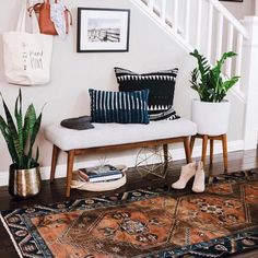 a white bench sitting in the middle of a living room next to a stair case