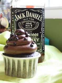 a cupcake sitting on top of a table next to a bottle of jack daniels