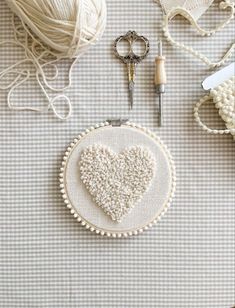 a close up of a heart on a table with yarn and scissors next to it