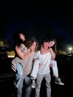 three people are posing for the camera at night with their arms around each other,