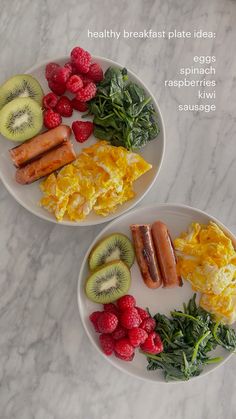 two white plates topped with breakfast foods on top of a marble countertop next to raspberries and kiwi slices