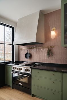 Green kitchen cabinet with pink backsplash and brass details. Gas stove with plaster canopy hood. Kitchens 2023, Green Kitchen Inspiration, Green Kitchens, Sage Kitchen, Pink Cabinets, Green Backsplash, Colourful Kitchen, Sage Green Kitchen