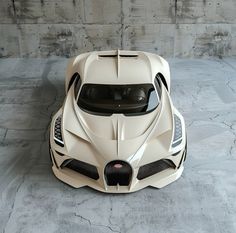 a white sports car parked in front of a concrete wall with no one around it