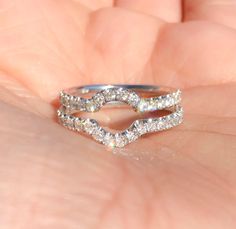 a close up of a person's hand holding a ring with diamonds on it