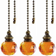 three orange glass balls hanging from a metal ball with chains attached to them, and one is