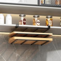 the spice rack has five jars on it and is attached to the wall above the counter